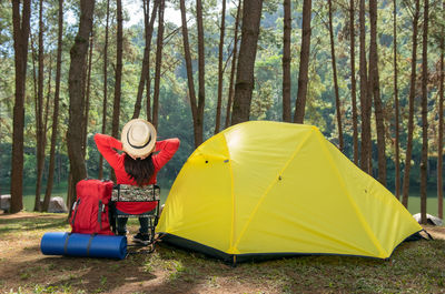 Rear view of woman sitting on tent in forest