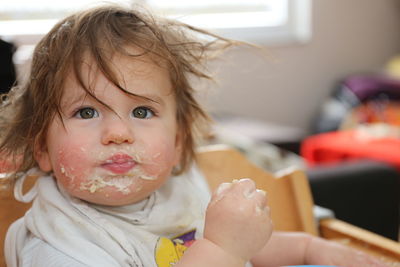 Portrait of messy girl eating food at home