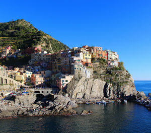 Townscape by sea against clear blue sky