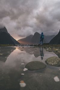 Young woman stands at the view of mitre peak in milford sound, nz
