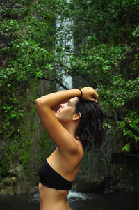 Side view of young woman standing in forest