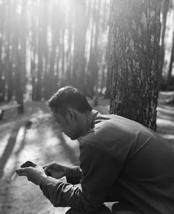 Young man using mobile phone in forest