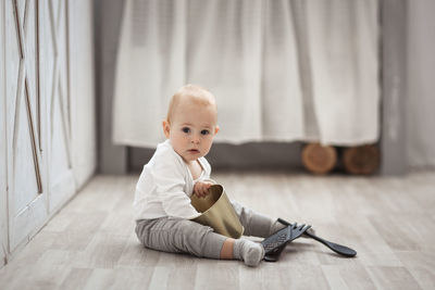 The blond kid plays with the kitchen tools on the floor, the concept of childhood and safety.