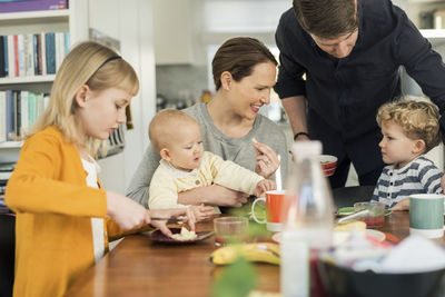 Happy family eating breakfast at table in living room