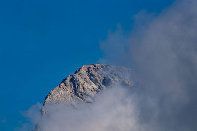 Low angle view of snowcapped mountains against blue sky