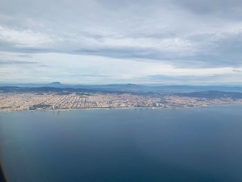 Aerial view of city by sea against sky