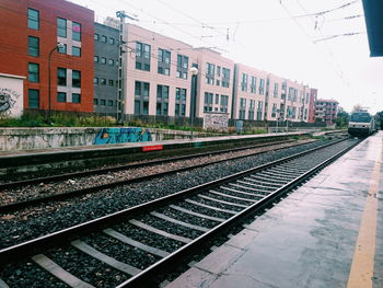 Railroad tracks in city against sky