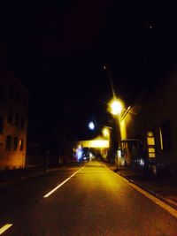 Road passing through illuminated city at night