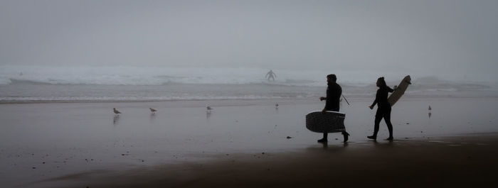 Silhouette people on beach against sky