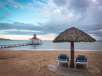 Lifeguard hut on beach against sky during sunset