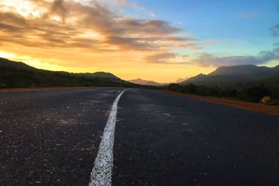 Surface level of road against sky during sunset