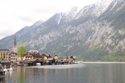 Houses by lake and mountains against sky