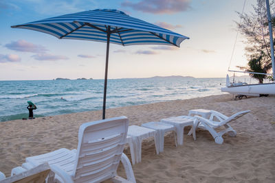 Deck chairs and parasols on beach against sky