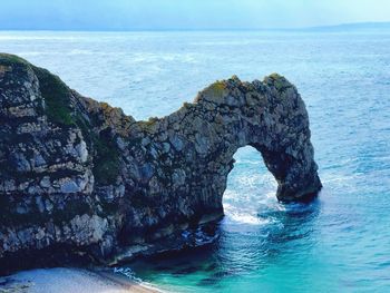 Rock formation on sea shore against sky