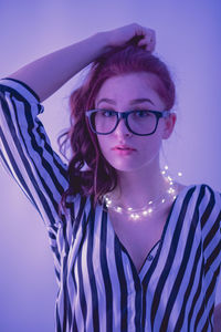 Young woman with illuminated string light against blue background