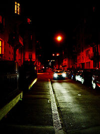 Illuminated street amidst buildings in city at night