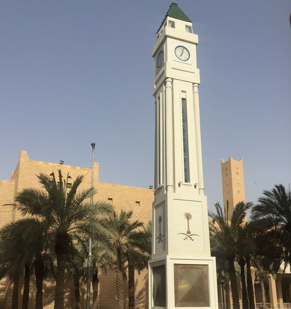 LOW ANGLE VIEW OF CLOCK TOWER AND PALM TREES AGAINST SKY
