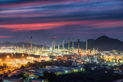 Illuminated factory against sky at night