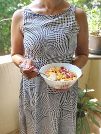 Midsection of woman holding bowl of cornflakes