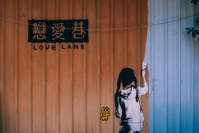 Woman standing by text on wall