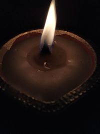 Close-up of burning candle against black background