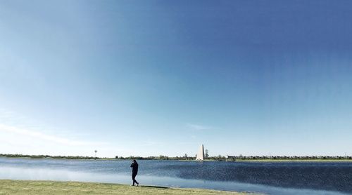 Side view of a silhouette man walking by the lake