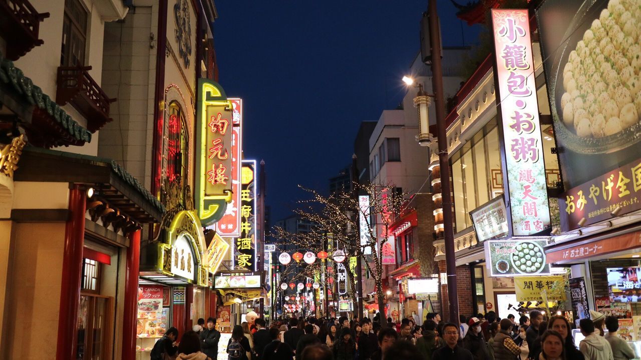 architecture, built structure, building exterior, illuminated, large group of people, night, city, person, men, lifestyles, city life, crowd, street, leisure activity, lighting equipment, celebration, building, outdoors, market