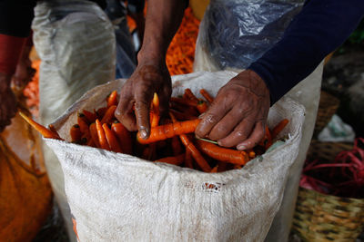 Close-up of man preparing carrots for sale