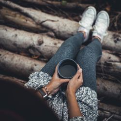 High angle view of woman holding coffee cup while sitting outdoors