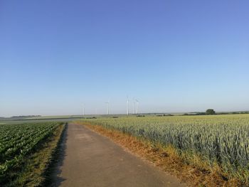 Road amidst field against clear sky