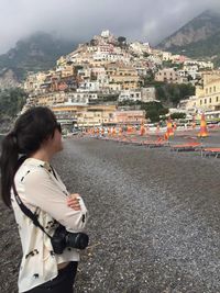 Side view of woman standing with dslr camera at beach in positano