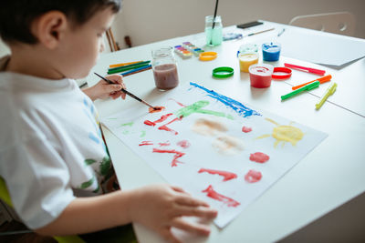 Boy doing painting while sitting at home