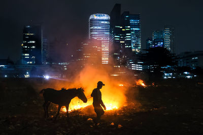 People standing by illuminated buildings in city at night