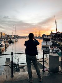 Rear view of man looking at harbor against sky