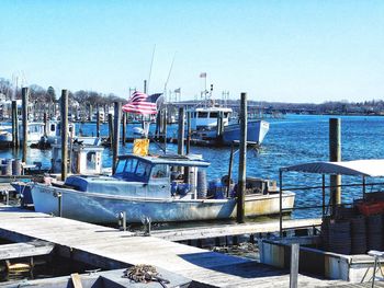 Boats moored at harbor against clear sky