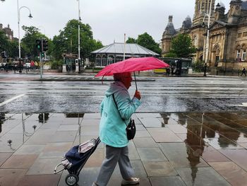 Woman walking on wet umbrella during rainy season