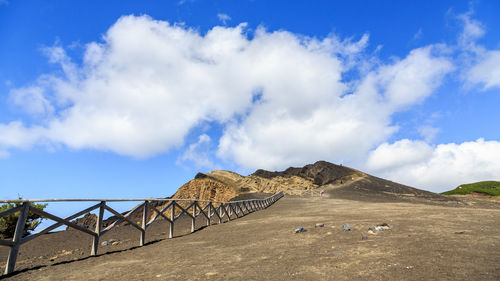 Road by bridge against blue sky