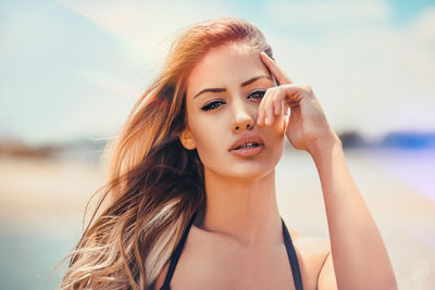 Close-up portrait of confident young woman at beach during sunny day