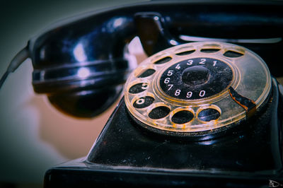 Close-up of black rotary phone by wall