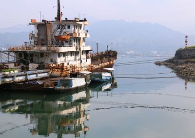 Ship moored in water against sky