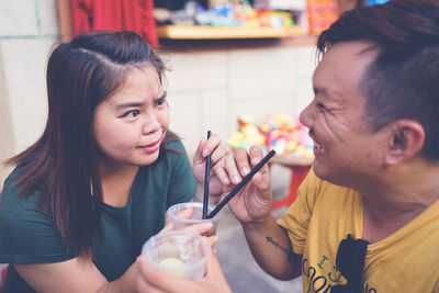 Close-up of a smiling man and woman drinking outdoors