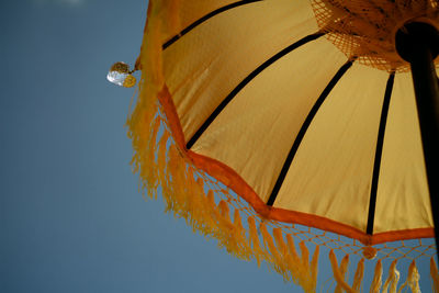 Low angle view of umbrella against clear blue sky
