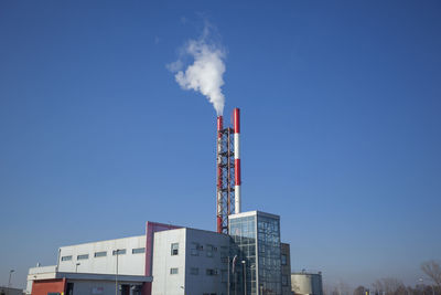 Smoke emitting from chimney against clear blue sky