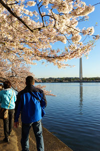 People walking by lake against washington monument during springtime