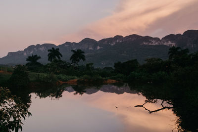 Scenic view of lake and mountains against sky at sunset