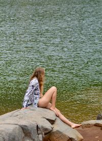 Woman sitting on rock looking at lake