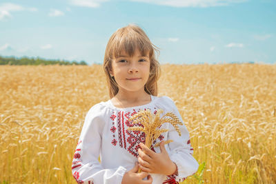 Portrait of cute girl holding wheat at farm