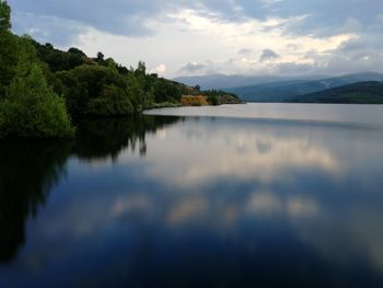 Scenic view of lake by trees against sky