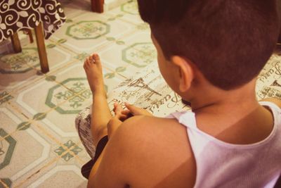 Rear view of boy sitting at home