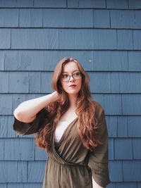 Thoughtful young woman standing against wall